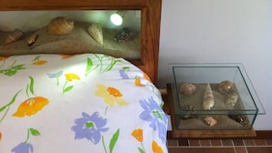 A bed with a floral bedspread and a glass terrarium with shells and a small turtle.