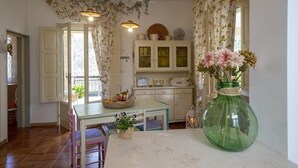 A cozy kitchen with a dining table, chairs, and a large green vase with flowers.