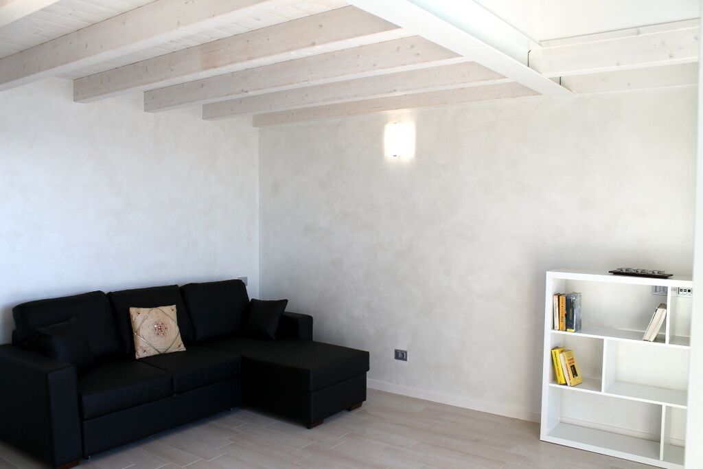 Un salon moderne avec un canapé d’angle noir, une étagère blanche et un plancher de couleur claire.