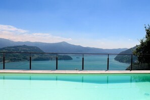 Ein Pool mit freiem Blick auf eine gebirgige Landschaft und ein Gewässer.