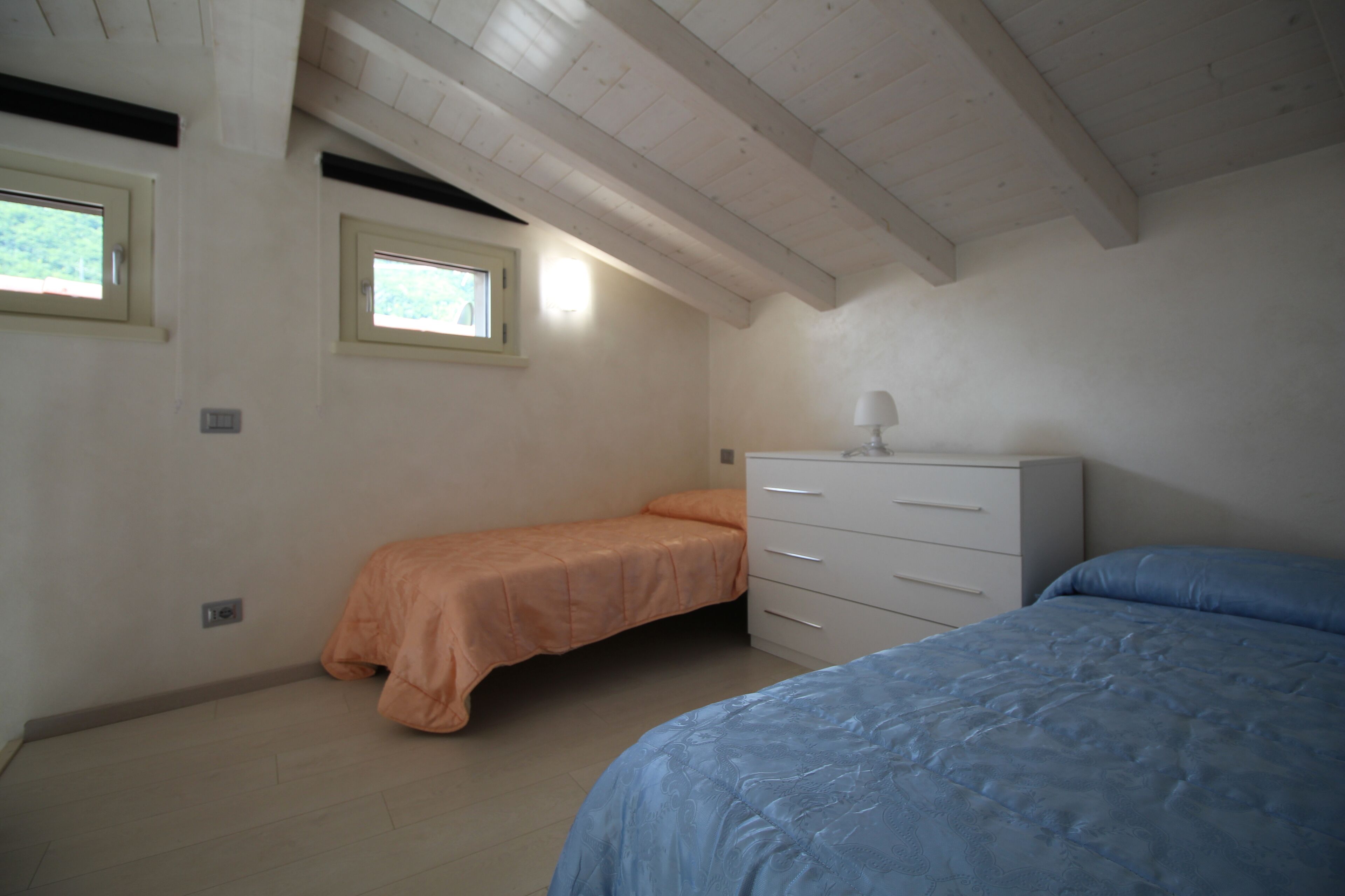 Un dormitorio con dos camas, un aparador y dos ventanas.