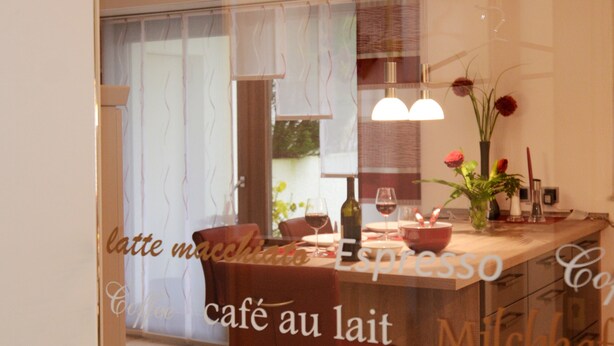 Ein Café mit Glasfassade, einer Holztheke und einer Sitzgelegenheit mit Stühlen.