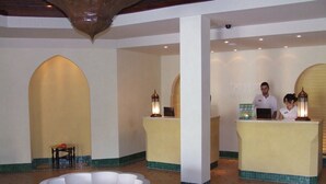 A lobby with a large white bathtub, reception desks, and a tiled floor.