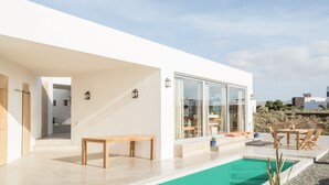 Une maison moderne dotée d’une piscine, de meubles en bois et offrant une vue sur le paysage environnant.