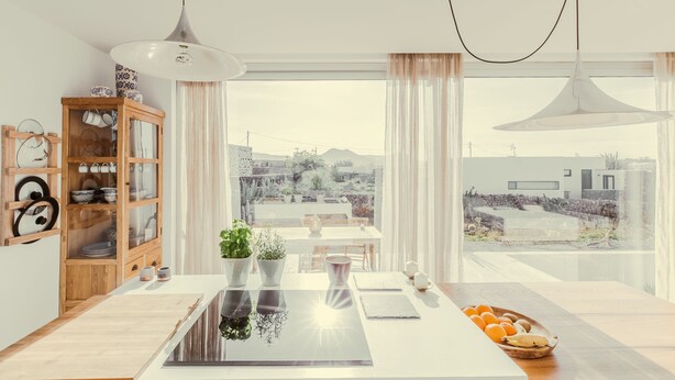 Une cuisine moderne dotée d’une grande fenêtre, de meubles en bois et d’un coin repas avec une table et des chaises.
