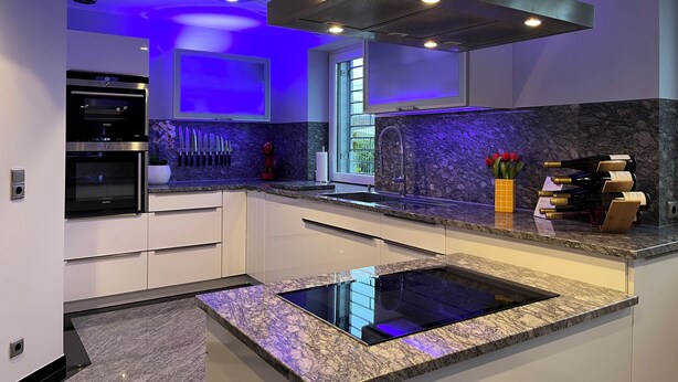 Una cocina moderna con electrodomésticos integrados, una isla central y un ventanal que proporciona luz natural.