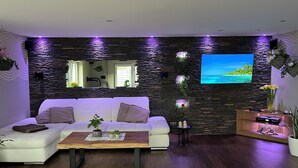 Una sala de estar moderna con un sofá blanco, una mesa de centro de madera y una pared de acento de piedra.