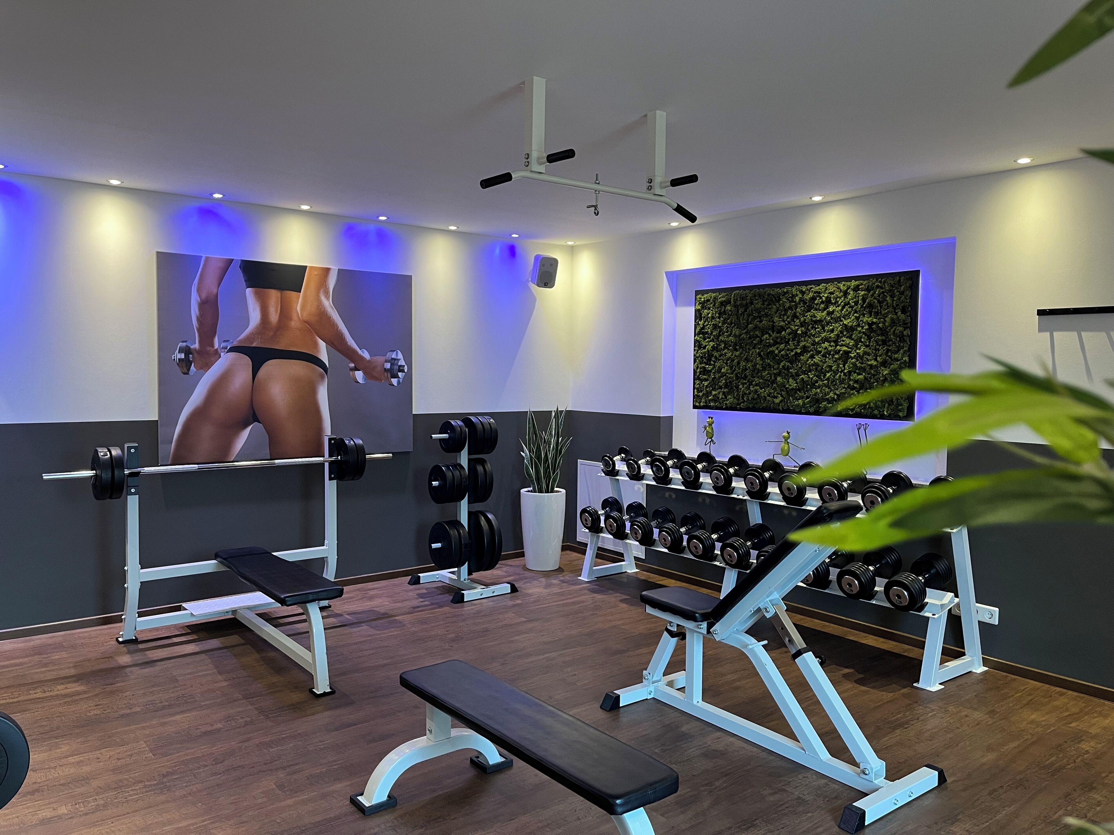 Ein modernes Fitnessstudio mit Krafttrainingsgeräten, Bänken und einem an der Wand montierten Fernseher.