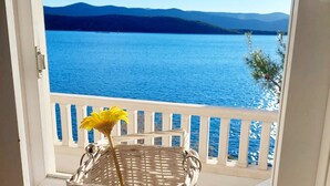 A wicker basket with a yellow flower on a balcony with a view of a blue sea and distant mountains. - House directly by the sea (Klek)