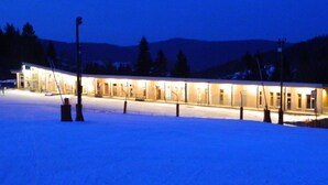 Un edificio con varias ventanas iluminadas rodeado de nieve.