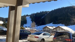 Un aparcamiento con coches, una estructura de madera y una montaña nevada al fondo.