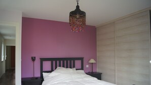 Un dormitorio con una cama, una mesita de noche, una lámpara y un aplique colgante.