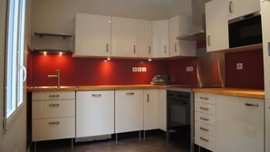 Una cocina moderna con armarios blancos, horno de acero inoxidable y una pared de acento roja.