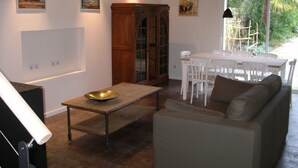 Una sala de estar con un sofá, una mesa de comedor con sillas, un armario y carteles en las paredes.