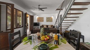 A dining area with a table set for four, a ceiling fan, and a staircase. - Villa Colibri - Three Bedroom Villa, Sleeps 6 (Le Vauclin)