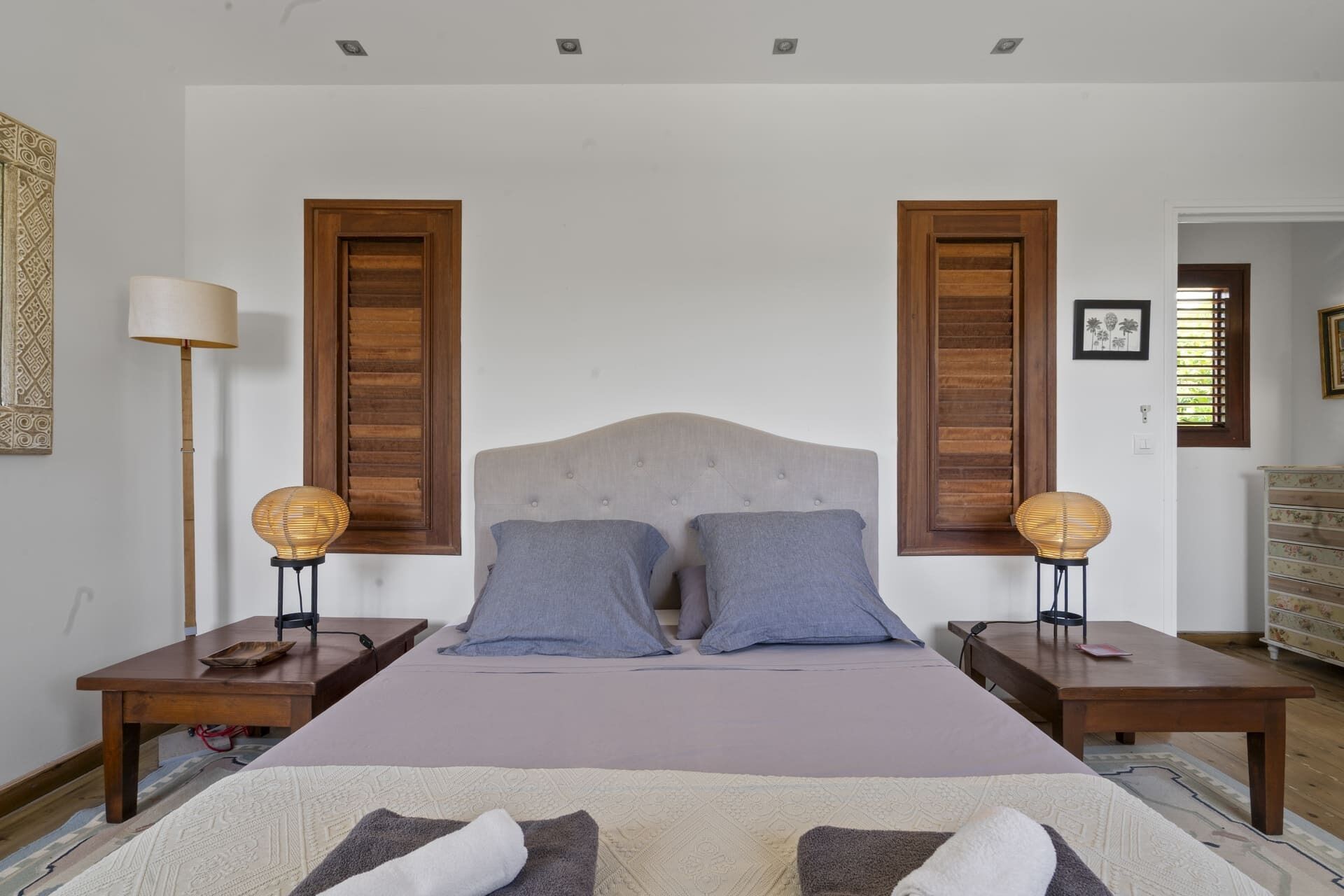 A bedroom with a bed, two nightstands, a lamp, and a dresser.