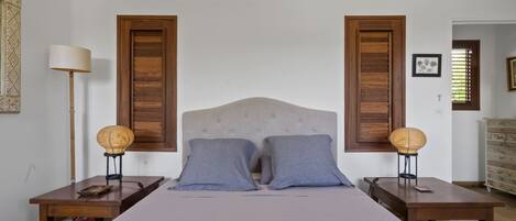 A bedroom with a bed, two nightstands, a lamp, and a dresser.