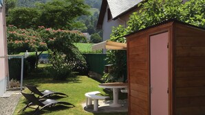 A backyard with a wooden shed, a table, and two chairs.
