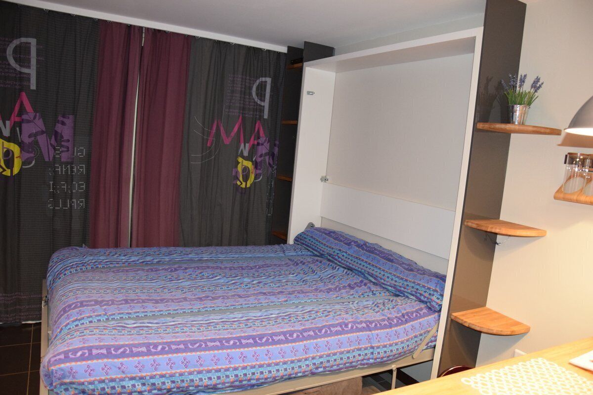 A bedroom with a bed, a wardrobe, and a desk area.