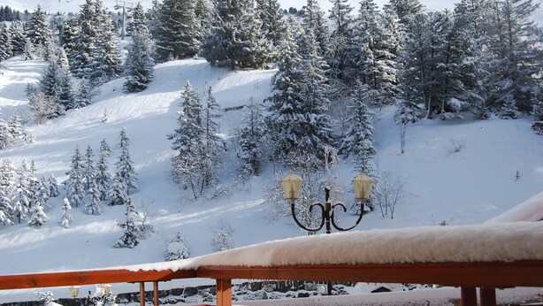 A snow-covered landscape with a wooden bench and a snow-covered lamp post.