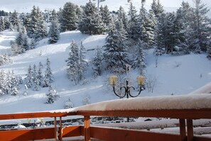 A snow-covered landscape with a wooden bench and a snow-covered lamp post.