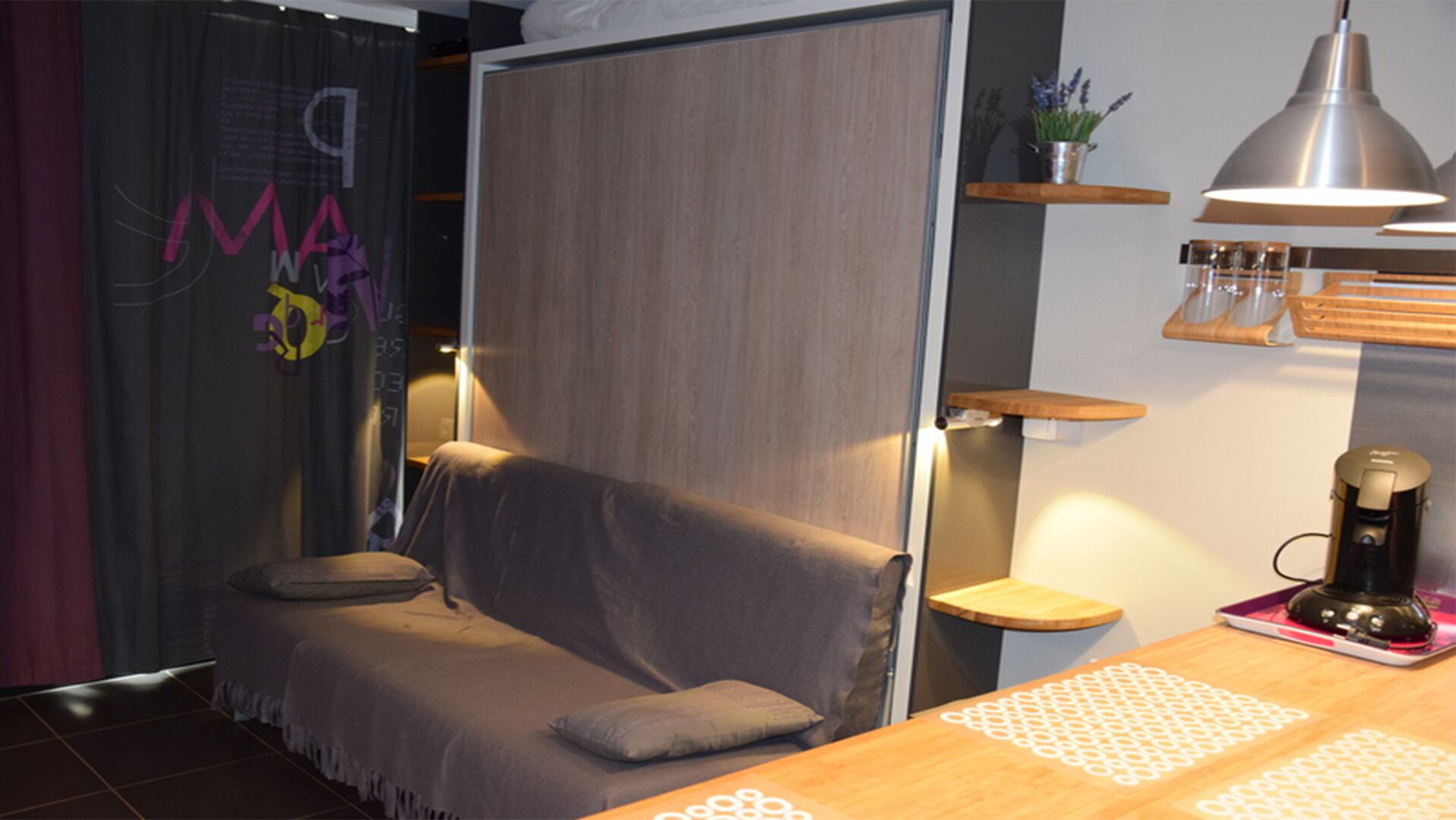 Ett modernt rum med en soffa, en kaffemaskin och ett litet bord i trä.