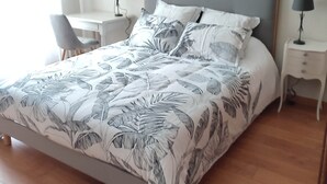 Una camera da letto con un letto grande, due comodini con lampade, una sedia, una scrivania e un quadro appeso al muro.