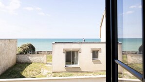 Un bâtiment moderne doté d’un toit plat et d’un petit balcon, offrant une vue sur une étendue d’eau.