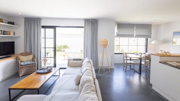 Un salon moderne comprenant un canapé, une table basse, un téléviseur et un coin repas avec une table et des chaises.
