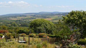 A rural landscape with rolling hills, a swing set, and a fenced garden area. -  Sea view with terrace and garden for hiking, sailing, beach ... (Crozon)