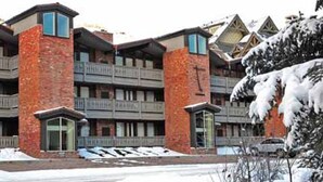 Un immeuble à plusieurs étages, doté d’une façade en briques, de balcons et surplombant un paysage enneigé.