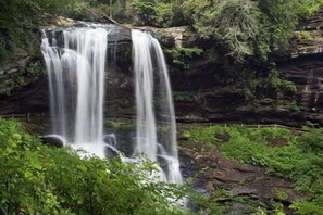 A waterfall cascading over a rocky cliff surrounded by lush greenery. - Cozy Condo in Sapphire NC (Sapphire)