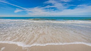 Una playa con cielos despejados y olas suaves.