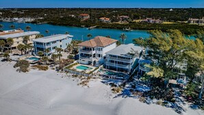 Un complejo turístico frente al mar con varias edificaciones, una piscina y una zona de playa.