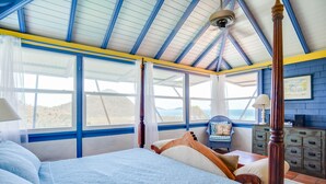 Quarto com cama de dossel, grandes janelas e vista para o exterior.