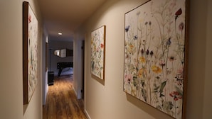 A hallway with wooden flooring, framed floral artwork on the walls, and a piano in the background. - Hot Tub Stream Stargazing Field Game Rm Telescope (Coudersport)