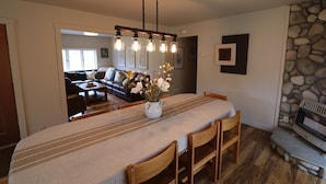 A dining area with a long table, chairs, a vase with flowers, a hanging light fixture, and a stone wall. - Hot Tub Stream Stargazing Field Game Rm Telescope (Coudersport)
