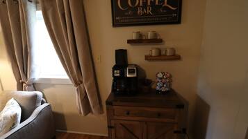 A cozy room with a coffee bar, a sofa, and a window with curtains.