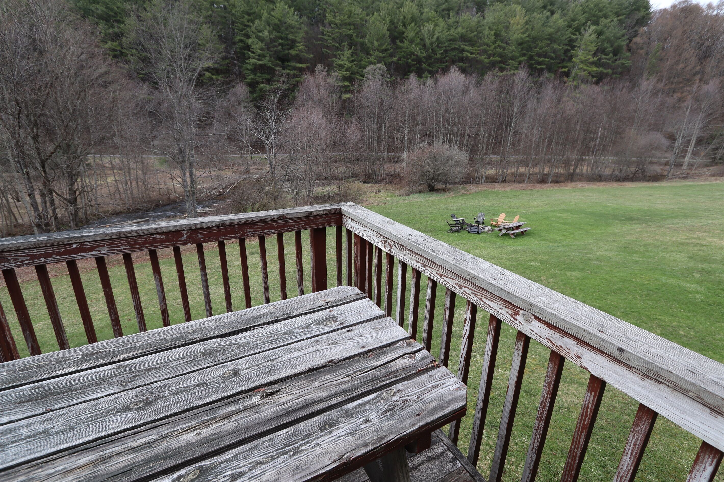Une terrasse en bois offrant une vue sur une pelouse et des arbres.