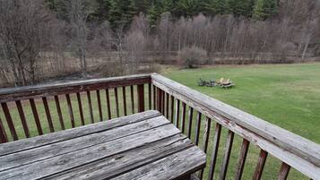 Une terrasse en bois offrant une vue sur une pelouse et des arbres.