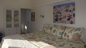 Ein Schlafzimmer mit einem Bett, einem Kleiderschrank und einem Wandbild mit Strandmotiv.