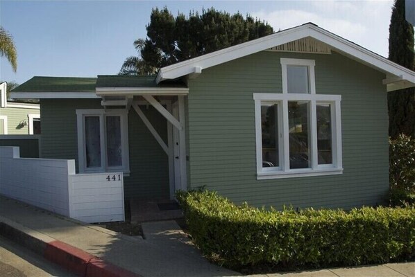 A small, single-story house with a green exterior and white trim. It has a front door, a small porch, and a visible number '441' on the side. - Historic Cottage 2 blocks to Beach & Town (Laguna Beach)