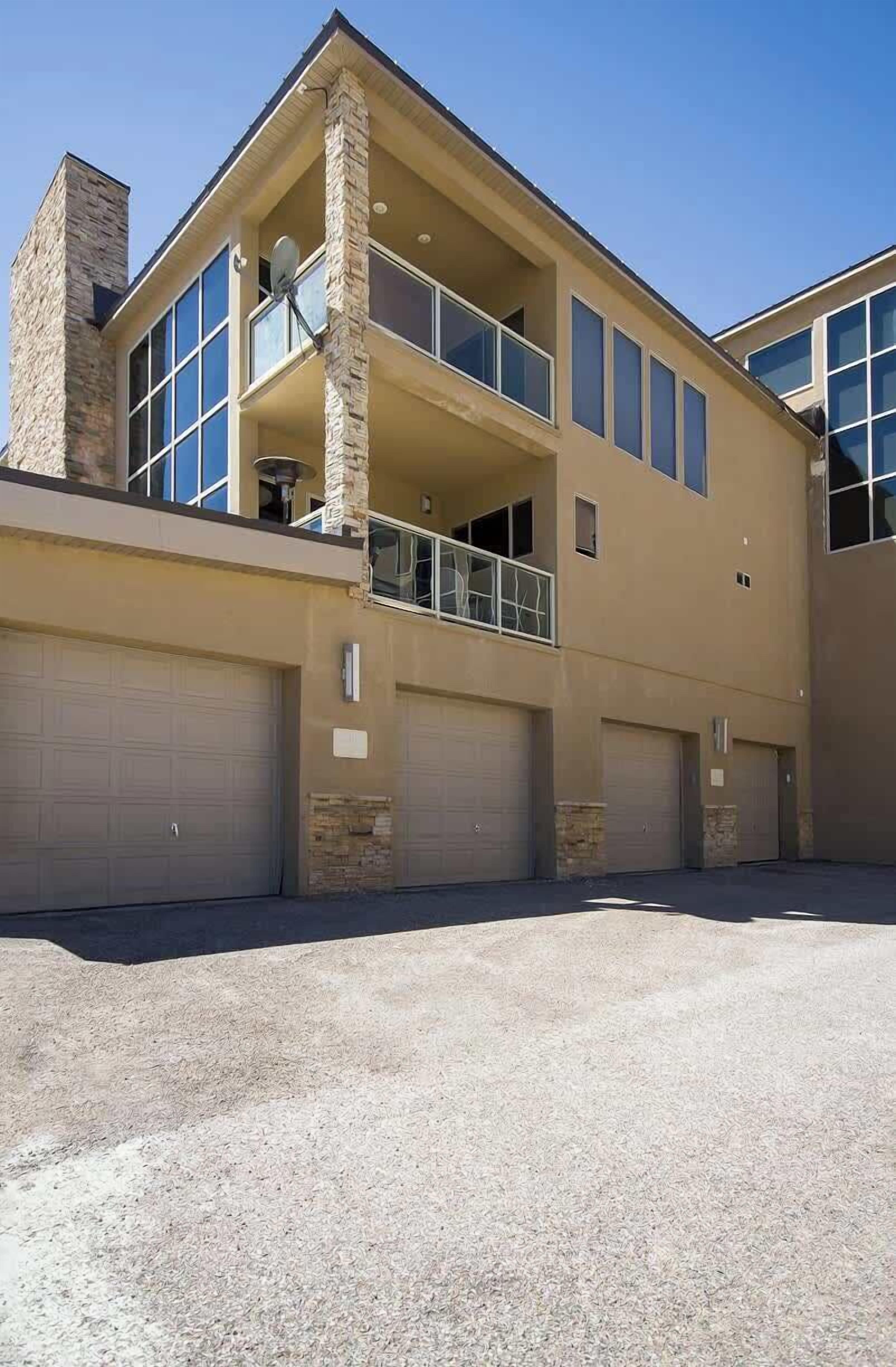 Ein zweistöckiges Haus mit Balkon, großen Fenstern und einer Garage.