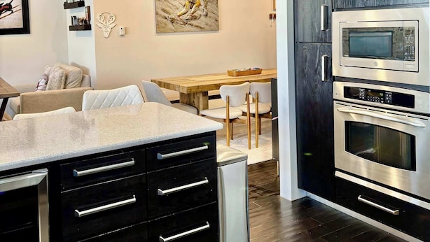 A modern kitchen with dark wood cabinets, stainless steel appliances, and a central island with drawers. - Lofts 2-A-Stunning Condo Right Across From Ski Resort (Brian Head)