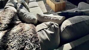 A modern living room with a large window, a stone fireplace, a mounted TV, and a cozy seating area. - Lofts 2-A-Stunning Condo Right Across From Ski Resort (Brian Head)