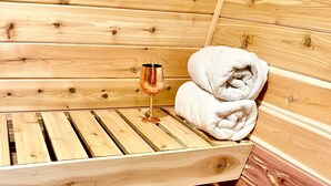A wooden sauna with a bench, a glass, and a towel.