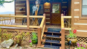 A wooden cabin with a wooden deck, a staircase, and a sign that reads "Mountain Valley View."