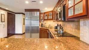 A modern kitchen with granite countertops, stainless steel appliances, wooden cabinets, and a microwave. - Gorgeous 1BR/2BA - Great Views & Reviews (Kapaa)