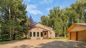 A single-story house with a front porch, a garage, and a gravel driveway.