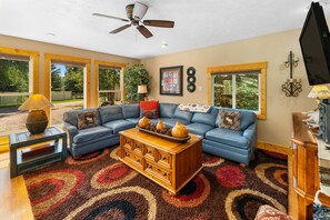 A living room with a sectional sofa, a coffee table with decorative items, a wooden cabinet, and a television.